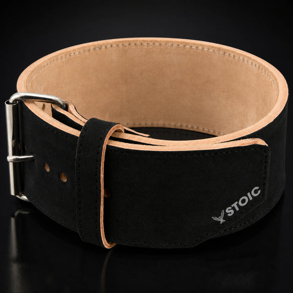 Stoic 10mm single-prong weight lifting belt in black, the belt coiled into a ring, seen from the front with the buckle at the left and the tan suede interior visible.