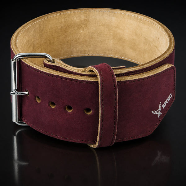 Stoic 10mm single-prong weight lifting belt in maroon, the belt coiled into a ring, seen from the front with the buckle at the left and the tan suede interior visible.