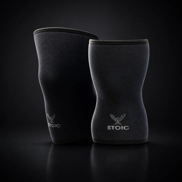Stoic 7mm knee sleeves for weightlifting in Black Label, the pair standing upright, showing the contoured anatomical shape.