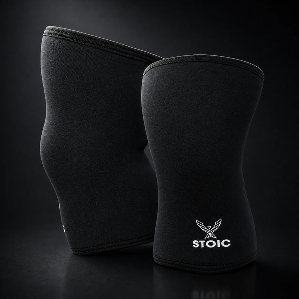 Stoic 7mm knee sleeves for weightlifting in black, the pair standing upright, showing the contoured anatomical shape.