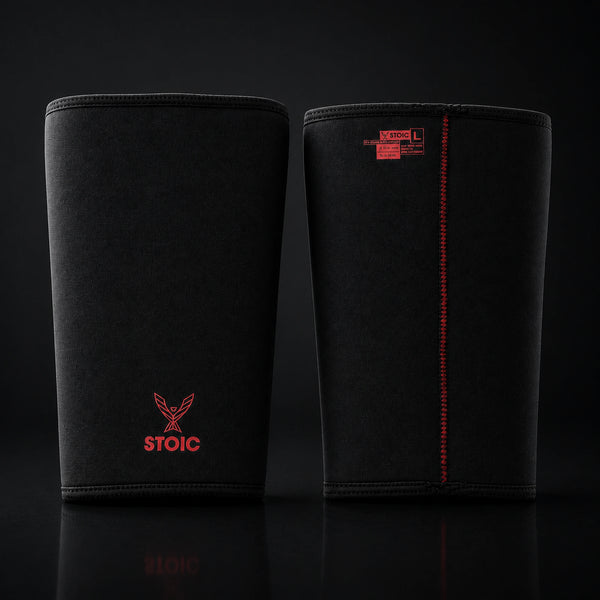 Stoic 7mm knee sleeves for weightlifting in Bloodline red and black, the pair standing side by side, one showing the phoenix logo on its front and the other showing the woven size and care label.