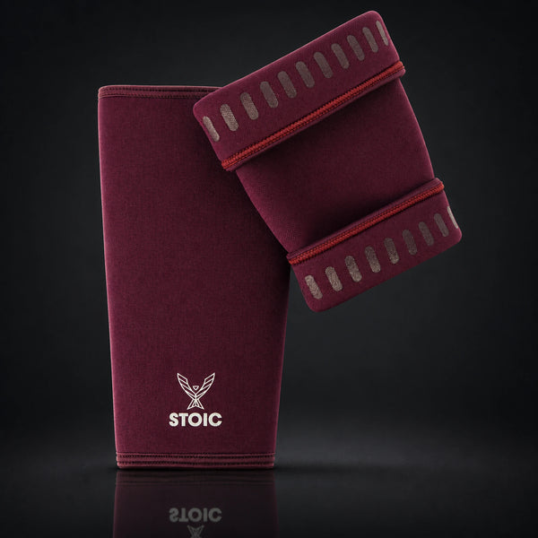 Stoic 7mm knee sleeves for weightlifting in maroon, the pair arranged with one sleeve showing the phoenix logo on its front and the other turned to reveal the silicone grip dashes inside the cuffs.