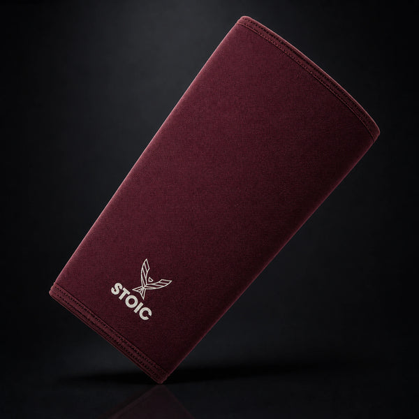Stoic 7mm knee sleeves for weightlifting in maroon, a single sleeve leaning at an angle, front face with the phoenix logo.
