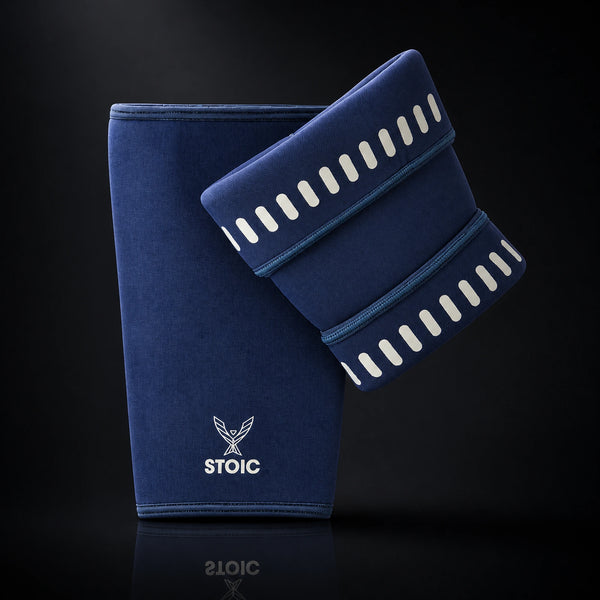 Stoic 7mm knee sleeves for weightlifting in navy, the pair arranged with one sleeve showing the phoenix logo on its front and the other turned to reveal the silicone grip dashes inside the cuffs.