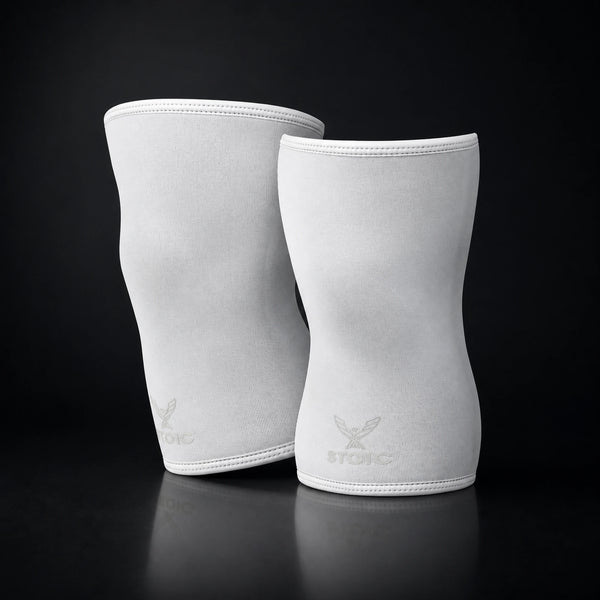 Stoic 7mm knee sleeves for weightlifting in white, the pair standing upright, showing the contoured anatomical shape.