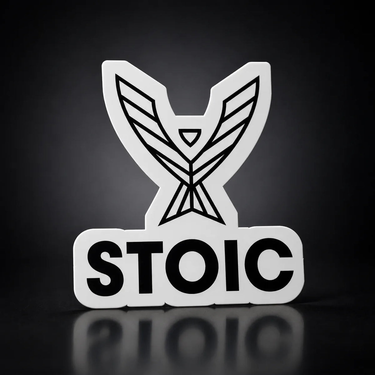 Stoic die-cut vinyl sticker, 2.75 inch, white vinyl with the black phoenix and STOIC logo, on a dark studio background