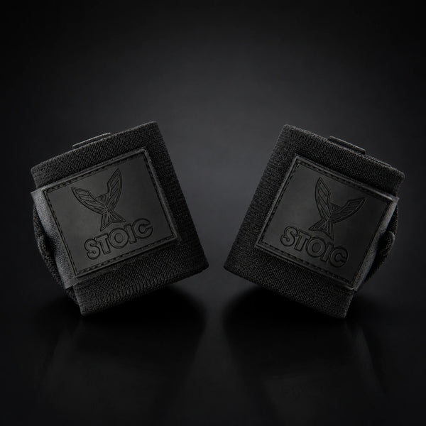 Stoic wrist wraps for weightlifting in Black Label, two rolled wraps tilted toward each other, logo patches facing the camera.