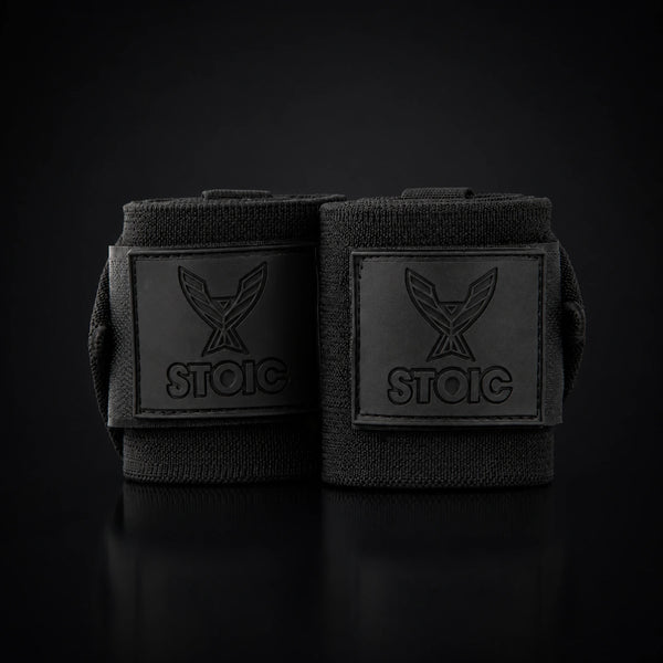 Stoic wrist wraps for weightlifting in Black Label, two rolled wraps standing together, both logo patches facing the camera.