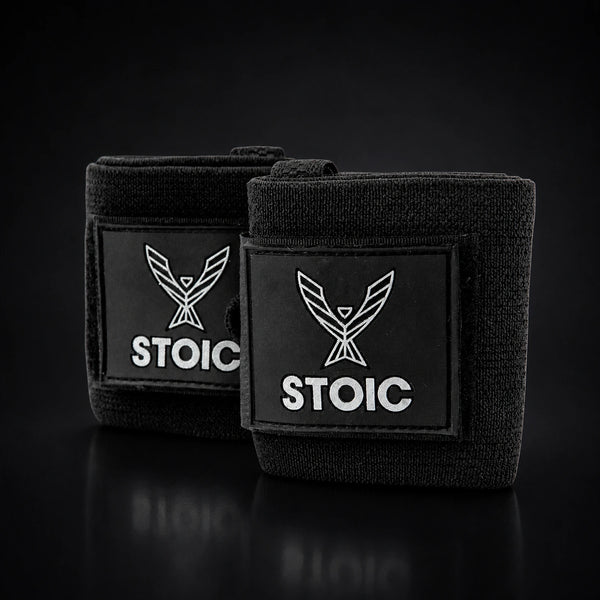 Stoic wrist wraps for weightlifting in black, two rolled wraps overlapping, both logo patches facing the camera.