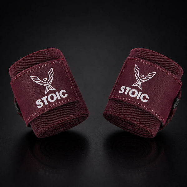 Stoic wrist wraps for weightlifting in maroon, two rolled wraps tilted toward each other, logo patches facing the camera.