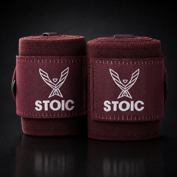 Stoic wrist wraps for weightlifting in maroon, two rolled wraps standing together, both logo patches facing the camera.