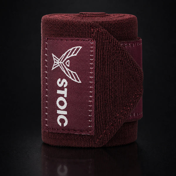 Stoic wrist wraps for weightlifting in maroon, a single rolled wrap with the hook-and-loop strap lifted away.