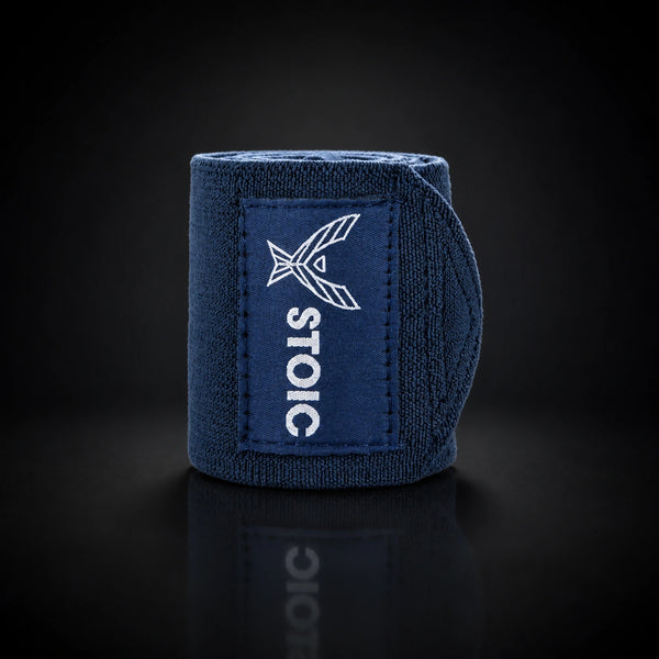 Stoic wrist wraps for weightlifting in navy, a single rolled wrap standing, with the elastic tail curling around behind it.