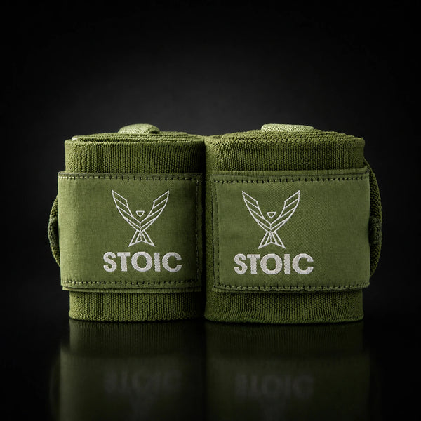 Stoic wrist wraps for weightlifting in olive drab, two rolled wraps standing together, both logo patches facing the camera.
