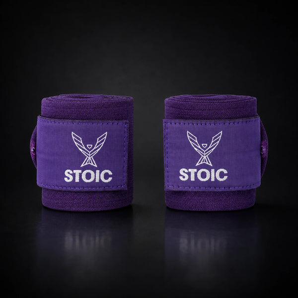 Stoic wrist wraps for weightlifting in purple, two rolled wraps standing apart, both logo patches facing the camera.