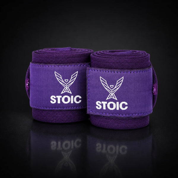 Stoic wrist wraps for weightlifting in purple, two rolled wraps standing together, both logo patches facing the camera.