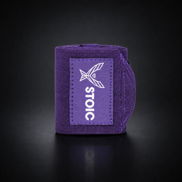 Stoic wrist wraps for weightlifting in purple, a single rolled wrap standing, with the elastic tail curling around behind it.