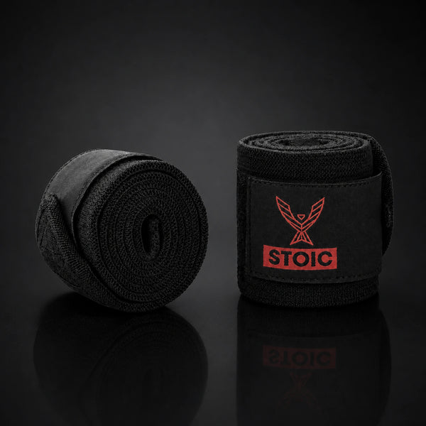 Stoic wrist wraps for weightlifting in Bloodline red and black, a flat coil of the wrap beside a rolled wrap.