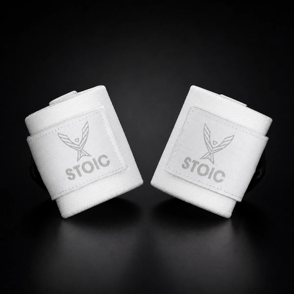 Stoic wrist wraps for weightlifting in white, two rolled wraps tilted toward each other, logo patches facing the camera.