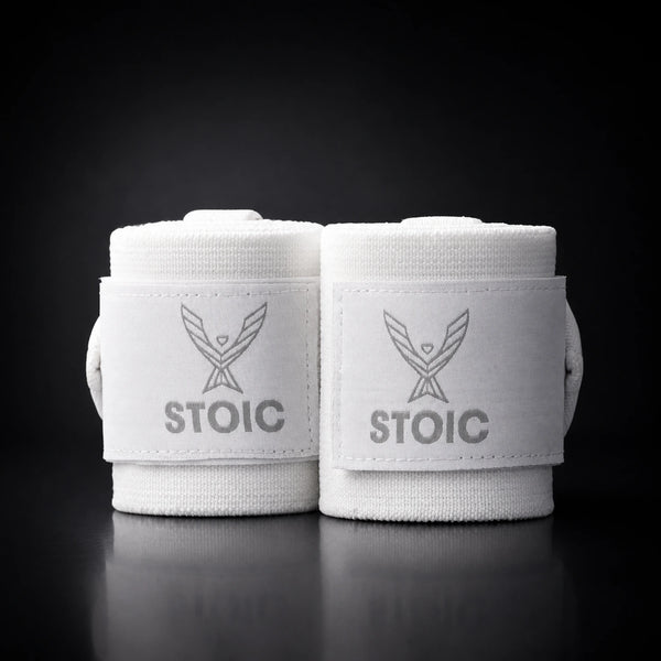 Stoic wrist wraps for weightlifting in white, two rolled wraps standing together, both logo patches facing the camera.