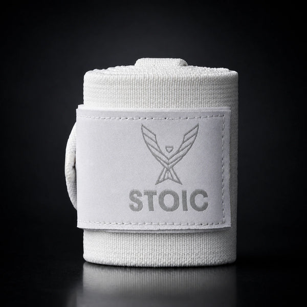 Stoic wrist wraps for weightlifting in white, a single rolled wrap standing, with the elastic tail curling around behind it.